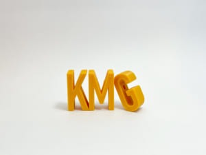 黄色いフィラメントでプリントした文字。KとMが自立していて、GがMに立てかけられている